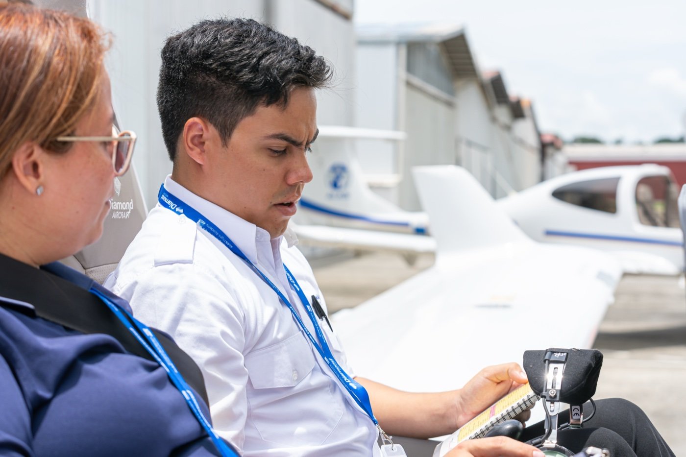Instructora y estudiante de ALAS Flight Academy revisando un briefing de vuelo junto a una aeronave Diamond